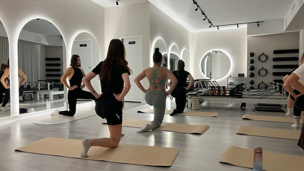 Grupa kobiet wykonuje ćwiczenia pilates na matach w studiu w Łowiczu